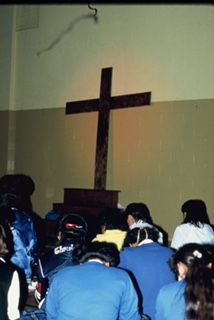 People Praying In Front Of A Cross